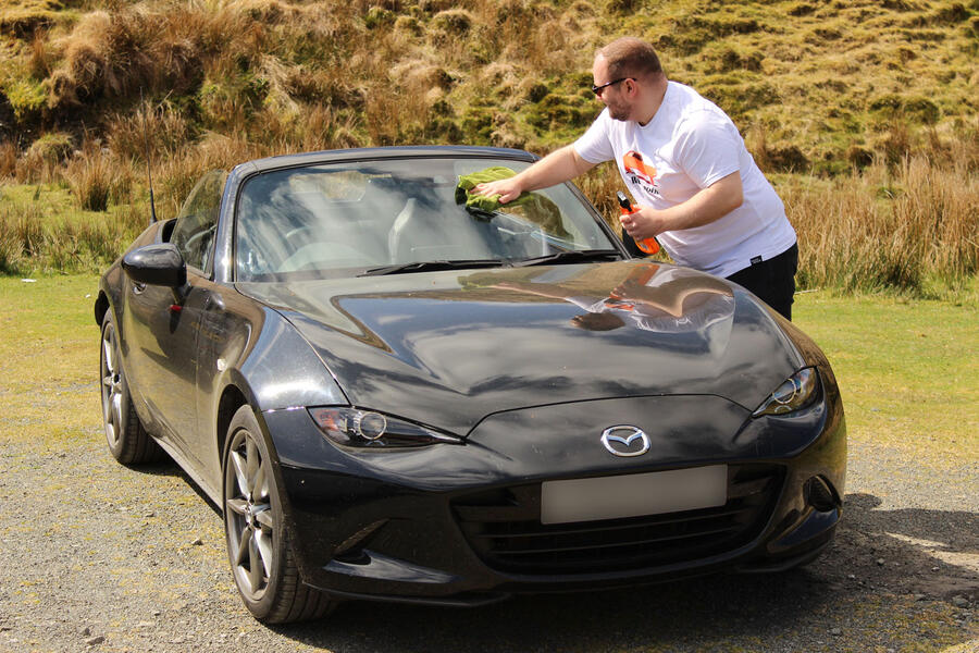 Charlie Martin cleaning Mazda MX-5 windscreen