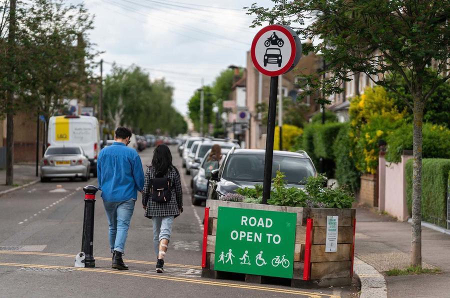 Duas pessoas atravessam a entrada de uma zona de baixo tráfego