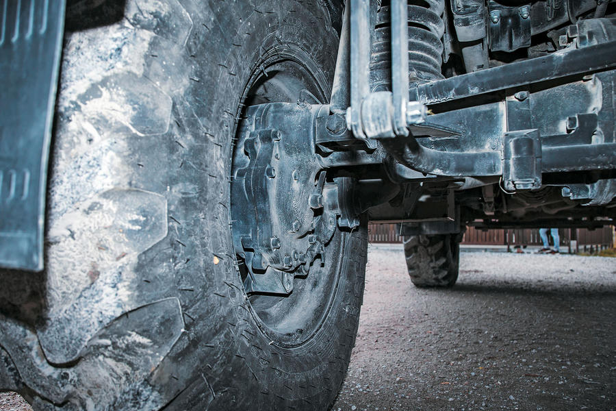 A close-up behind the wheel hub of a Unimog, showing its complex suspension and brakes