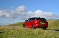 Red Vauxhall Astra estate drives up a hill   rear three quarters